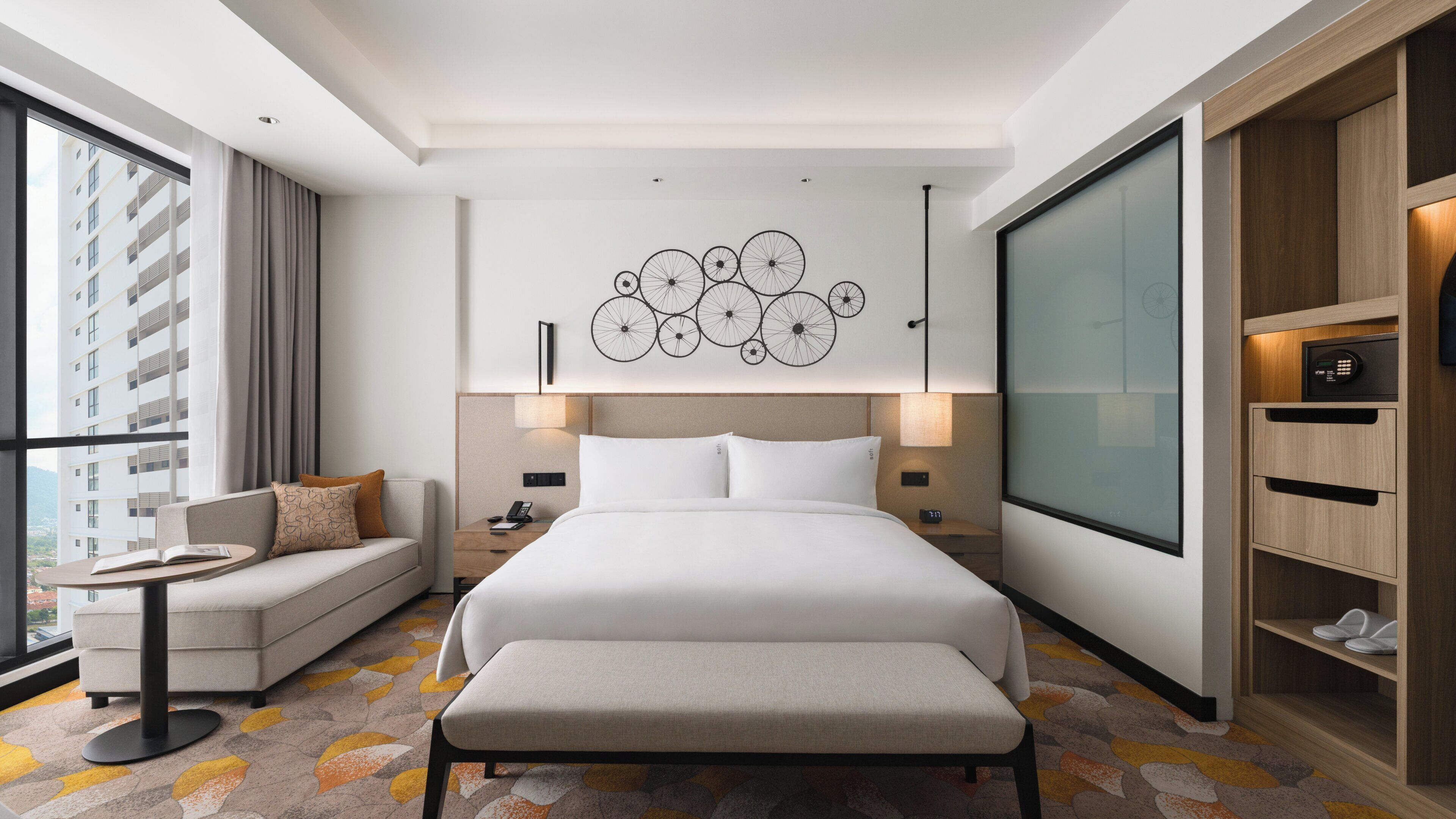Una camera d'albergo moderna con un letto grande, una poltrona, un tavolino e un armadio.