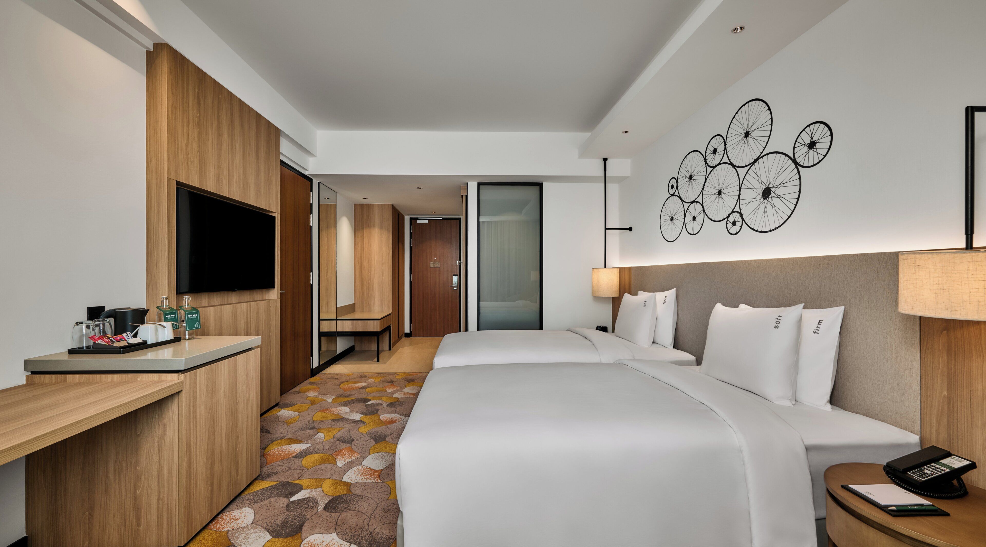 A hotel room with a bed, bedside table, and a desk with a flat-screen TV.