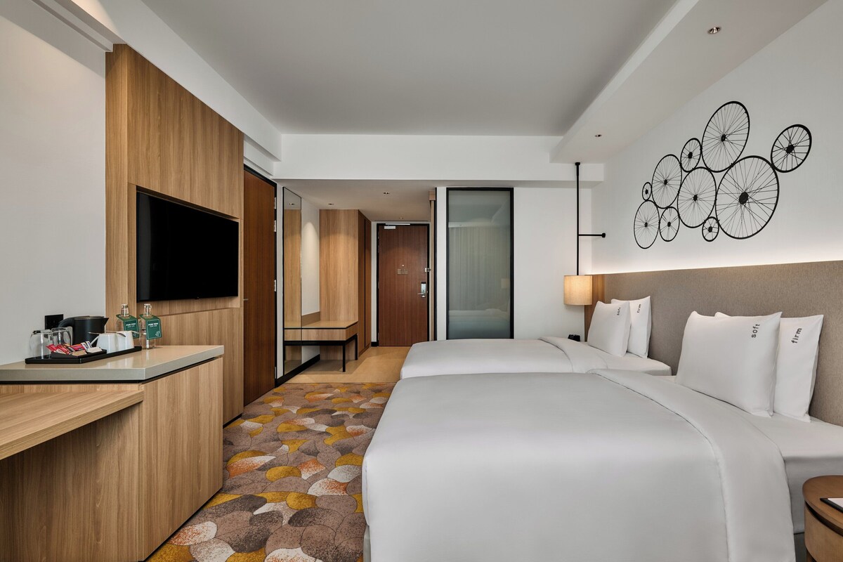 A hotel room with a bed, bedside table, and a desk with a flat-screen TV.