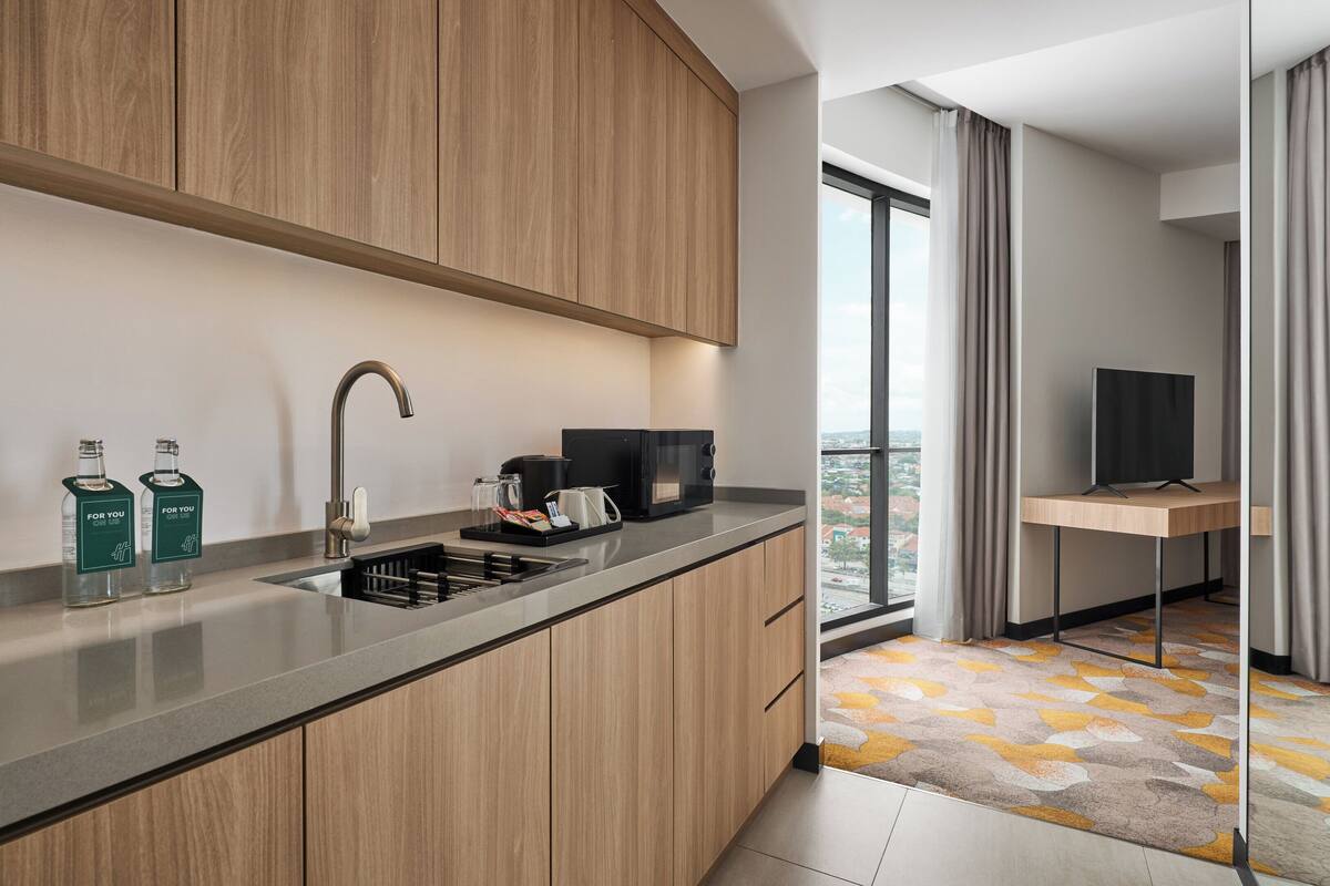 Une cuisine moderne avec des meubles en bois, un évier en acier inoxydable et un grille-pain encastré.