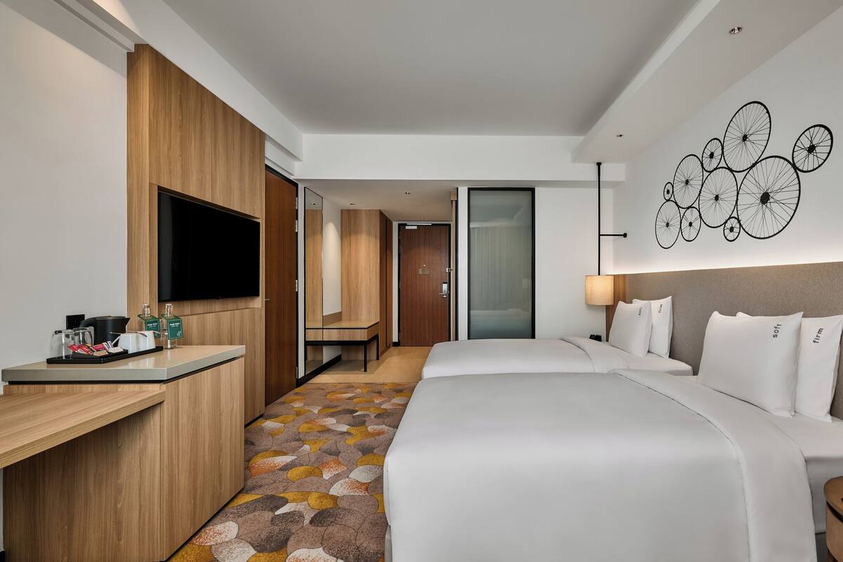 Une chambre d’hôtel équipée d’un lit, d’une table de chevet et d’un bureau avec un téléviseur à écran plat.
