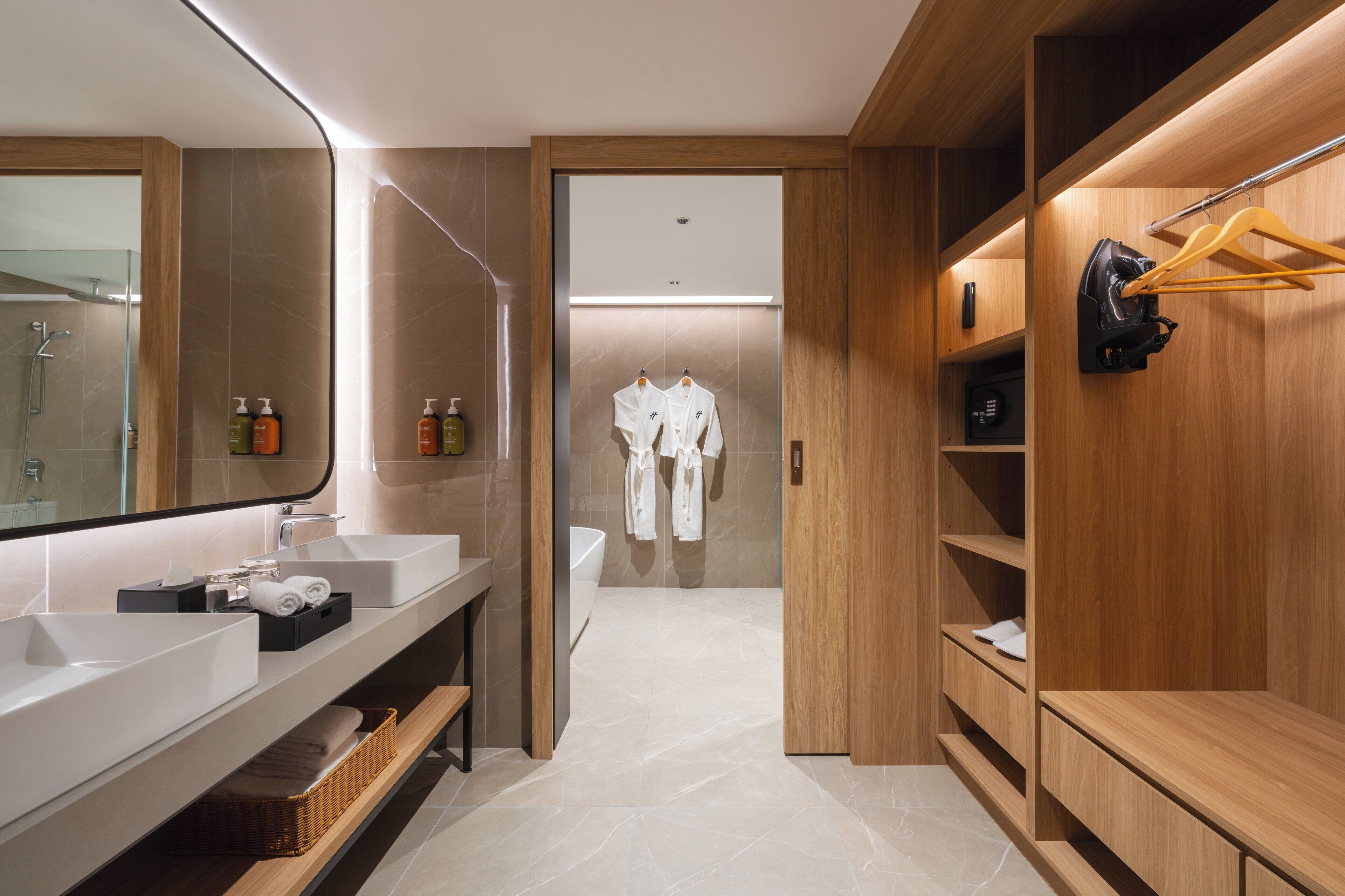 A modern bathroom with dual sinks, a large mirror, and a walk-in shower.