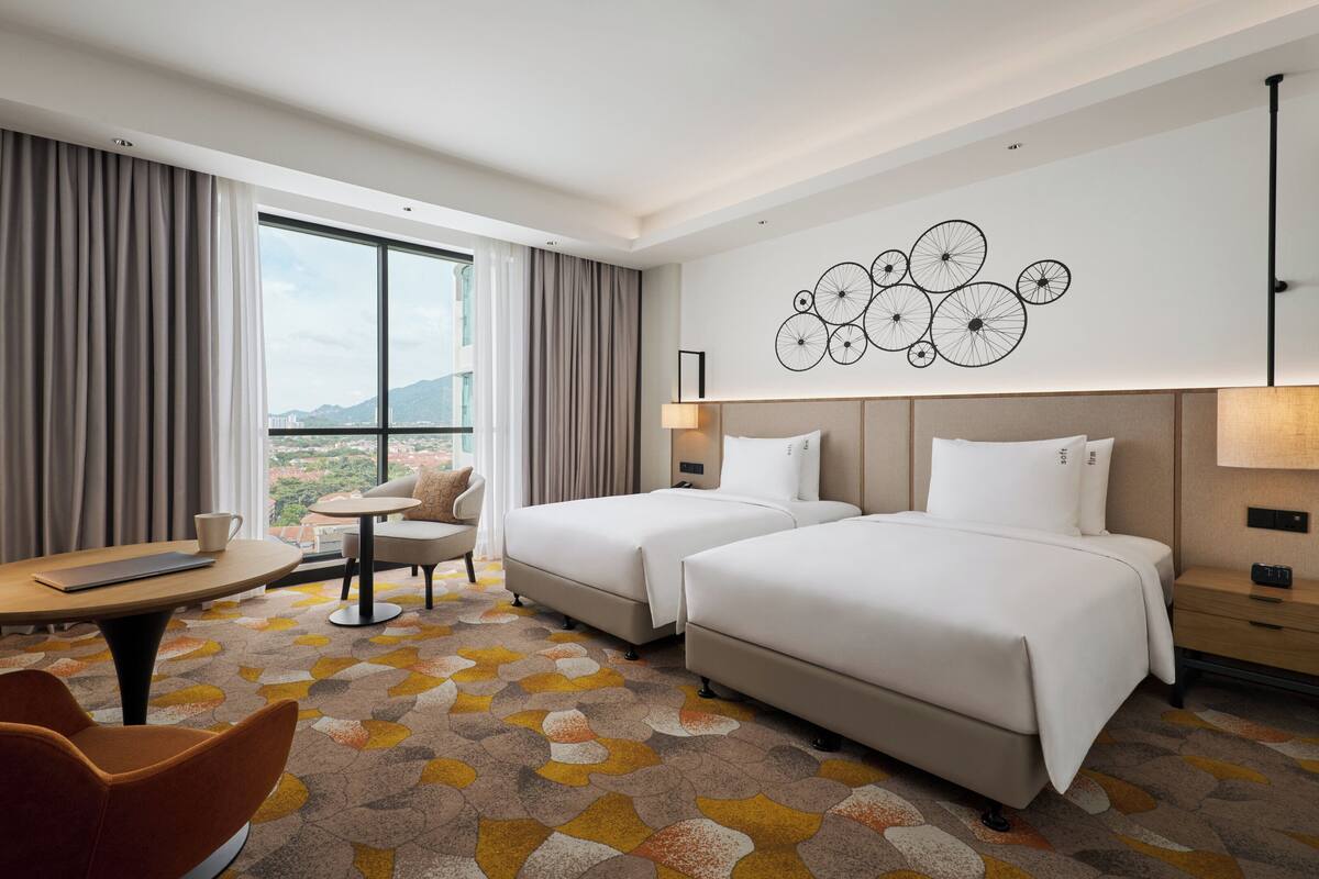 Une chambre d’hôtel avec deux lits, un bureau, une chaise et une vue sur la ville.