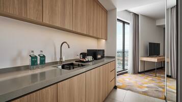 A modern kitchen with a built-in sink, wooden cabinets, and a view of the city through a large window.
