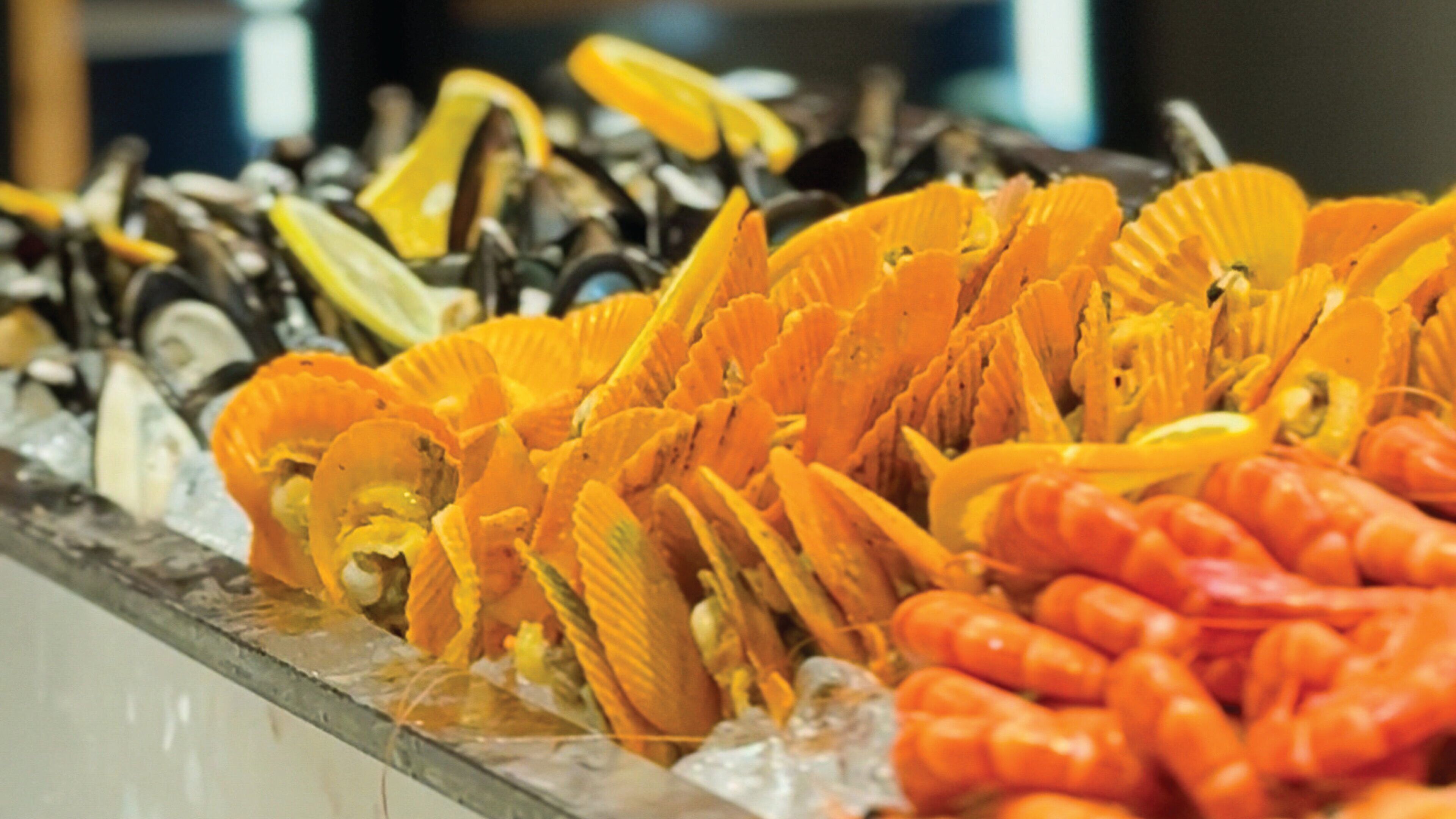 A buffet with various seafood items, including shrimp and scallops, displayed on a bed of ice.