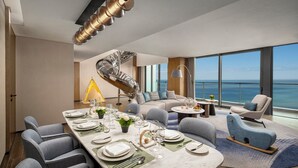 A modern dining area with a long table set for a meal, a spiral staircase, and a view of the ocean. - Crowne Plaza Sanya Yazhou Bay by IHG (Sanya)