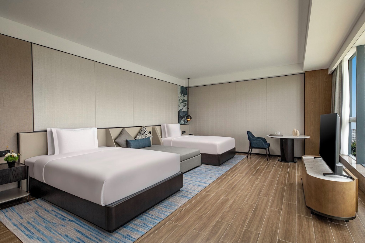Una habitación de hotel moderna con dos camas, un escritorio, una silla y un televisor.