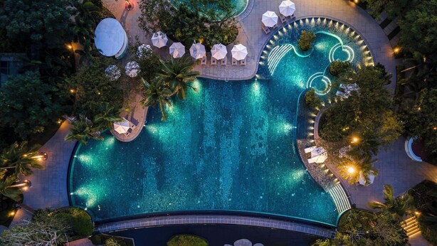 An aerial view of a resort with a large swimming pool surrounded by palm trees and lounge areas. - Crowne Plaza Sanya Yazhou Bay by IHG (Sanya)