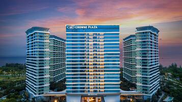 Un hôtel de grande hauteur, reconnaissable à son grand panneau « Crowne Plaza », doté de nombreux balcons et offrant une vue sur le front de mer.