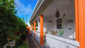 A narrow alleyway with a white building featuring orange pillars and a small porch with a hanging decoration. - Cozy studio in gorgeous Soufriere with WiFi, AC (Soufriere)