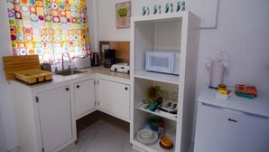 A compact kitchen with white cabinets, a microwave, and a coffee maker. - Cozy studio in gorgeous Soufriere with WiFi, AC (Soufriere)