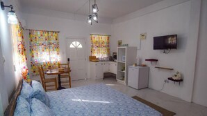 A bedroom with a bed, a desk, a chair, a small kitchenette, and a TV. - Cozy studio in gorgeous Soufriere with WiFi, AC (Soufriere)