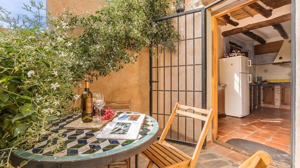 A cozy outdoor dining area with a mosaic table, a bottle of wine, and a glass. - El Garzopo Órgiva by Ruralidays (Granada)