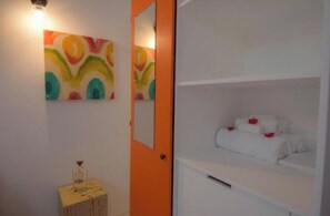 Simple, functional design with a single bed, colorful artwork, and a cozy seating area.