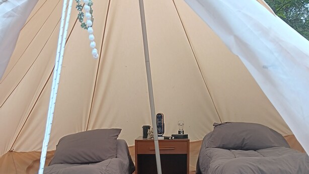 A tent with two beds, a small wooden table, and a patterned rug.