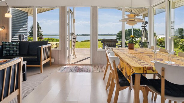Een modern interieur met een eethoek, een bank en uitzicht op een meer.