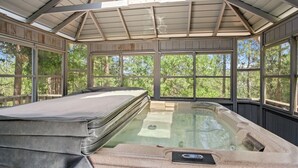 Een hottub met een deksel, omringd door houten wanden en grote ramen.