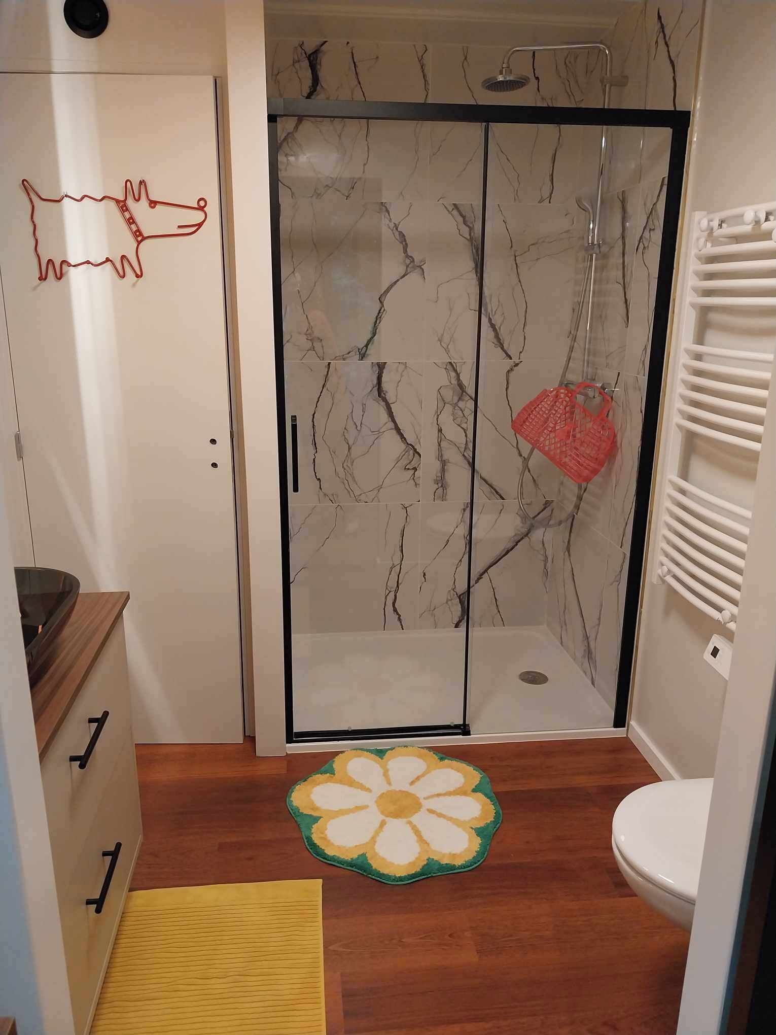 A bathroom with a shower, toilet, and a decorative rug.