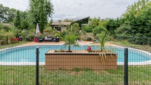 Un patio trasero con piscina, rodeado por una valla, y una casa al fondo.