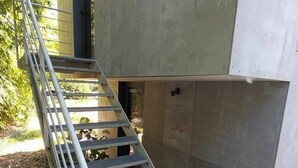 Una escalera metálica conduce a un edificio moderno con fachada de concreto.