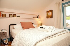 A neatly made bed with a white comforter and a brown pillow, a bedside table with a lamp, and a window with curtains. - 4BR Catskills Farmhouse on 26 Private Acres. Mountain Views, Sleeps 8 (Jefferson)