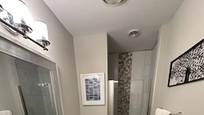 Casa de banho moderna com um lavatório duplo, um espelho grande, um chuveiro com porta de vidro e um tapete listrado no chão.