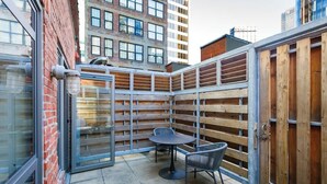 Eine Terrassenfläche mit Tisch und Stühlen, begrenzt von einem Holzzaun und Metalltoren.
