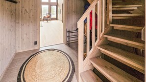 A wooden staircase with a rug at the bottom, leading to a room with a chair and a view through a glass door. - Stunning home in Vinje with WiFi (Vinje)