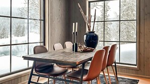 A dining area with a wooden table, chairs, a vase, and candles. - Stunning home in Vinje with WiFi (Vinje)