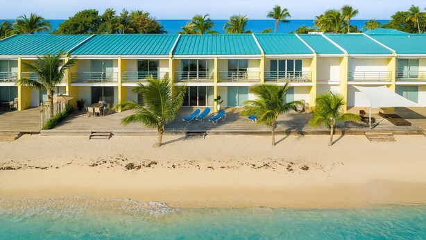 A beachfront hotel with a two-story structure, a covered patio, and a pool area with lounge chairs. - Cocos Beachfront Heaven (Simpson Bay)