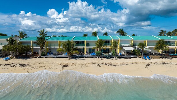 A beachfront hotel with multiple rooms, a pool area, and palm trees. - Cocos Beachfront Breeze (Simpson Bay)