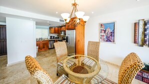 A modern living room with wicker furniture, a glass coffee table, and a chandelier. - Cocos Beachfront Breeze (Simpson Bay)