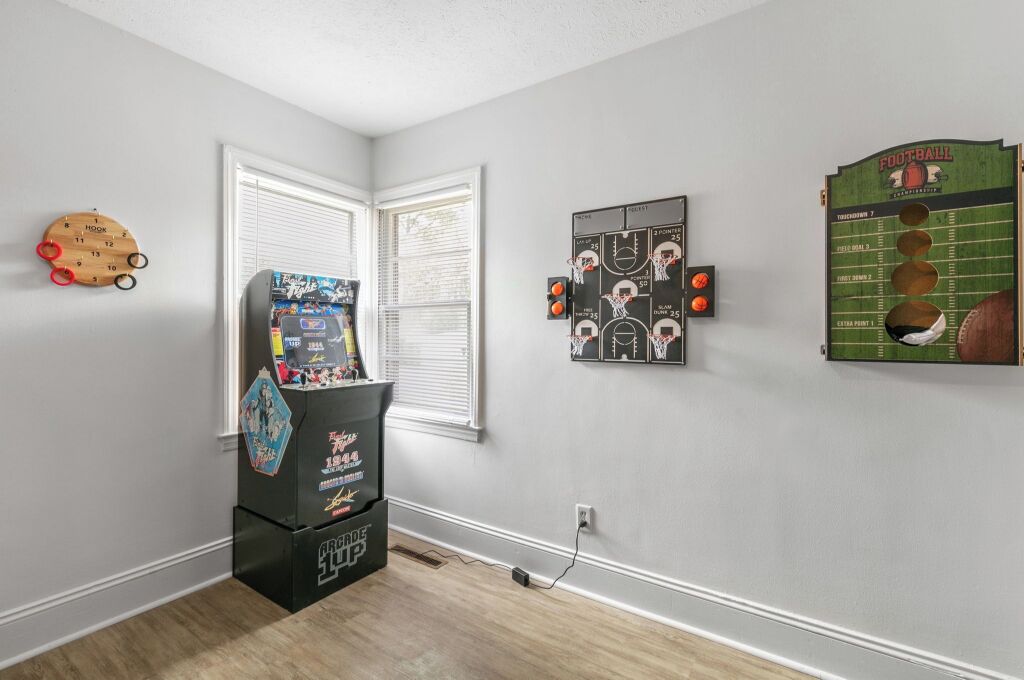 A room with a dartboard, a small arcade machine, and a football-themed wall decoration.