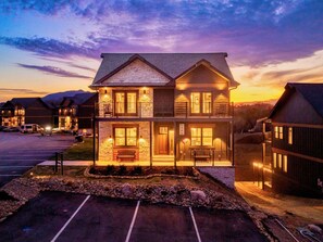 A two-story building with a stone facade, a covered front porch, and a parking lot. - Smith Creek Resort | Luxury 5BR Cabin | Lazy River, Indoor Pool, Hot Tub | 1 mile to Pigeon Forge (Sevierville)