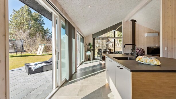 A modern kitchen with a large island, sliding glass doors leading to a patio, and a view of the outdoors.