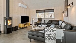 A modern living room with a fireplace, leather sofa, TV, and wooden walls.
