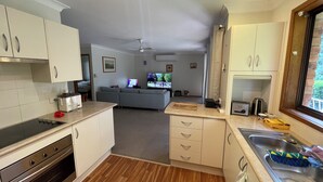 A compact kitchen with a built-in oven, a sink, and a dining area with a sofa.