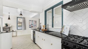 Eine moderne Küche mit weißen Schränken, einer schwarzen Arbeitsplatte, einem Herd und einem Fenster mit Vorhängen.
