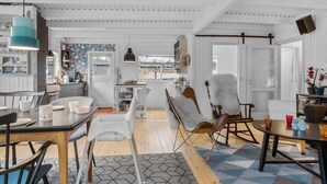 Een ruime keuken met witte kasten, een eethoek met een tafel en stoelen, en een gezellige zithoek met een schommelstoel en een zachte fauteuil.