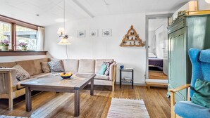 A cozy living room with a wooden coffee table, a sofa, a blue armchair, and a small side table. - 2 bedroom awesome home in Haarby (Haarby)
