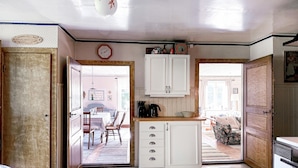 Una cocina compacta con armarios blancos, cafetera y comedor con mesa y sillas.