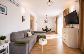 A modern living room with a grey sofa, a white coffee table, and a flat-screen TV mounted on a cabinet. - 3 bedroom beautiful home in Sutivan (Sutivan)