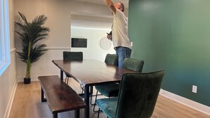A dining area with a wooden table and green chairs, a potted plant, and a ceiling light fixture. - Huge home w/ 4 king beds and a huger yard. On Grand River on 11 acres (Ada)