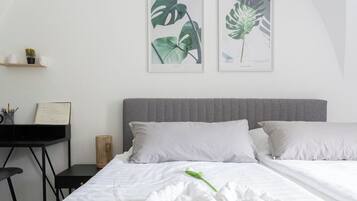 A modern hotel room with a bed, a desk, and two framed botanical prints on the wall.