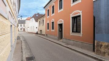 A narrow street lined with buildings featuring classic architecture and a cobblestone sidewalk.