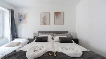 A modern hotel room with a large bed, two bedside tables, and a window with curtains.