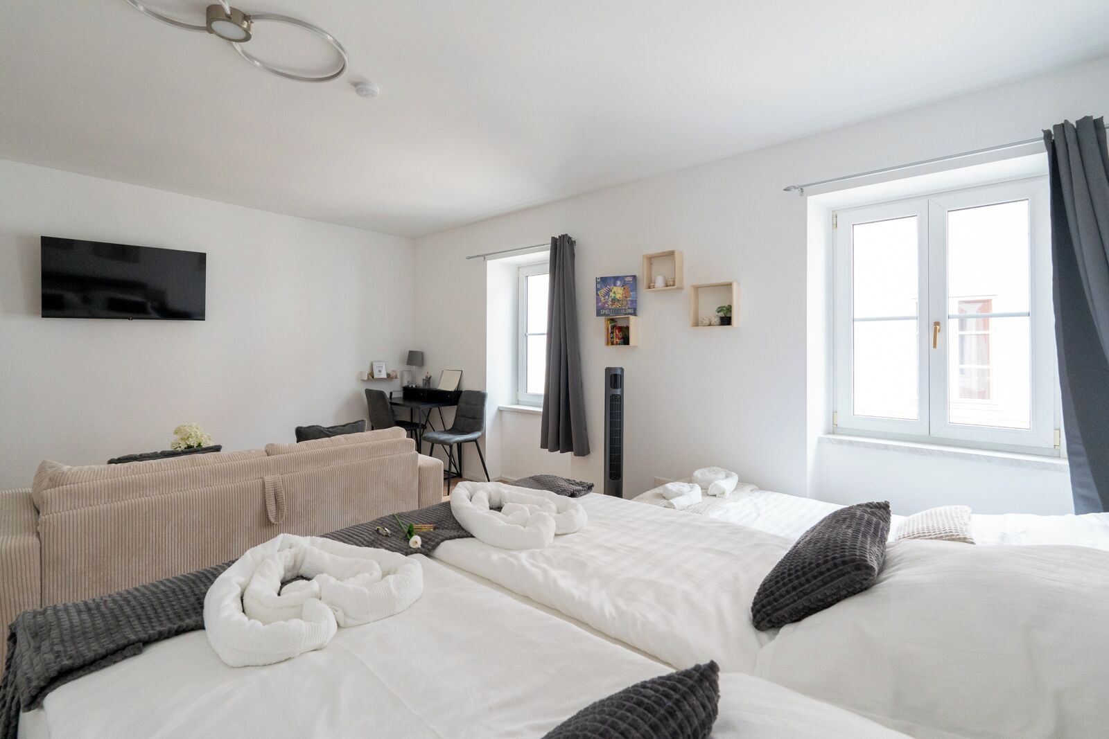 A hotel room with two beds, a desk, a chair, a TV, and a window with curtains.