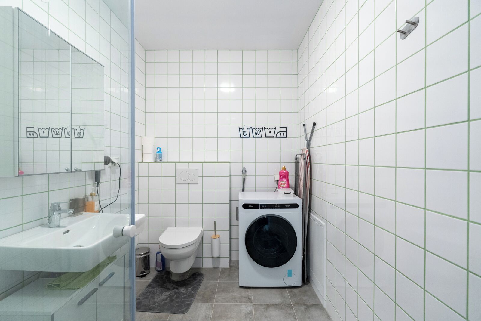 Een kleine badkamer met een wastafel, toilet en wasmachine.