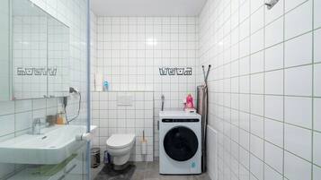 Ett litet badrum med handfat, toalett och tvättmaskin.