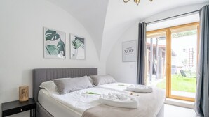 A modern bedroom with a large bed, a bedside table, and a view of the outdoors. - COY Apartments Wachau - Relaxation In Style (Mautern an der Donau)
